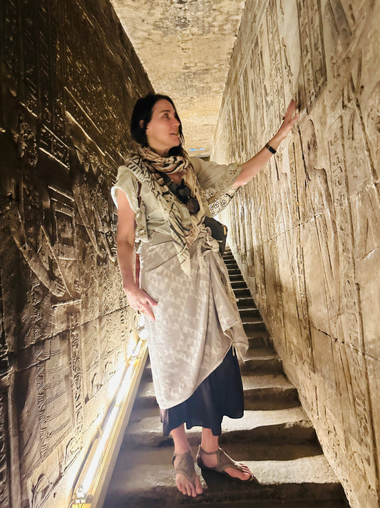 Stephanie standing in a temple corridor in Egypt, hand resting on a wall covered in hieroglyphs.