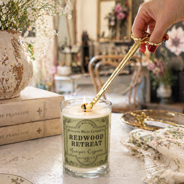 Soy wax candle being lit with gold wick trimmer at Duncans Mills Candle Co. fragrance bar
