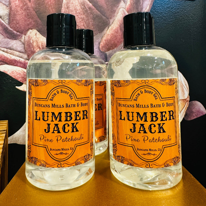 Bottle with flip top of bath & body gel called Lumberjack with fragrance notes of pine and patchouli.