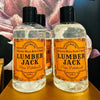 Bottle with flip top of bath & body gel called Lumberjack with fragrance notes of pine and patchouli.