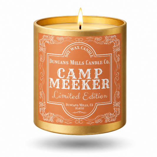A lit gold metal candle jar with a terracotta orange label reading 'Duncans Mills Candle Co. Camp Meeker Limited Edition' on a white background.