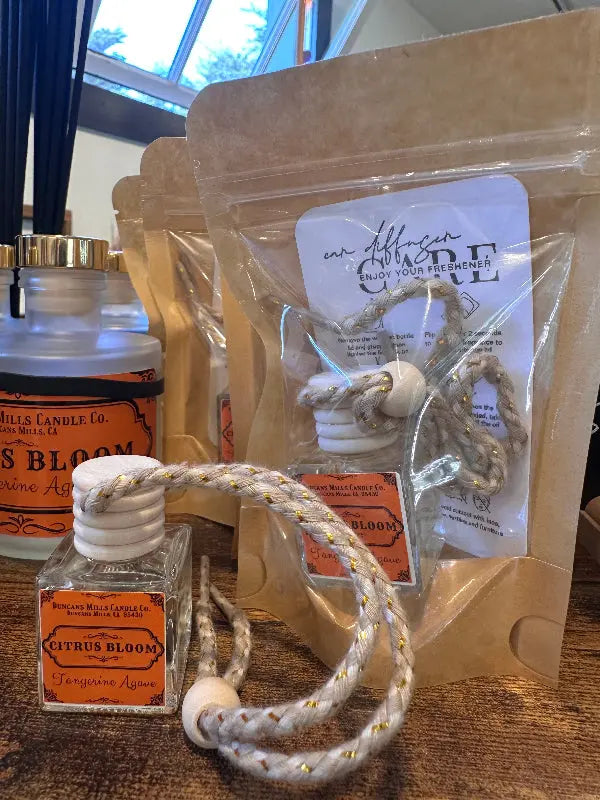 Small bottle with rope handle and orange label that says Citrus Bloom on a wooden surface.