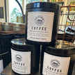Large black candle tins with lids and cream-colored label: Gold Coast Coffee & Bakery, Coffee
