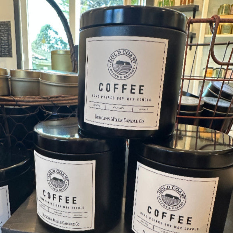 Large black candle tins with lids and cream-colored label: Gold Coast Coffee & Bakery, Coffee