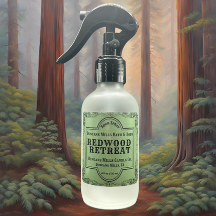 A bottle of Redwood Retreat Room & Linen Spray nestled in a graphic of redwood trees, capturing the fresh, earthy essence of the Russian River’s towering forests.