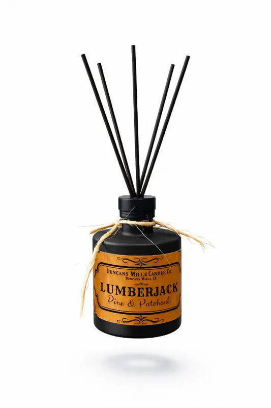 A bottle of Lumberjack Reed Diffuser with natural reeds, evoking the rugged scent of sugared pine and patchouli, inspired by the forests of Cazadero.