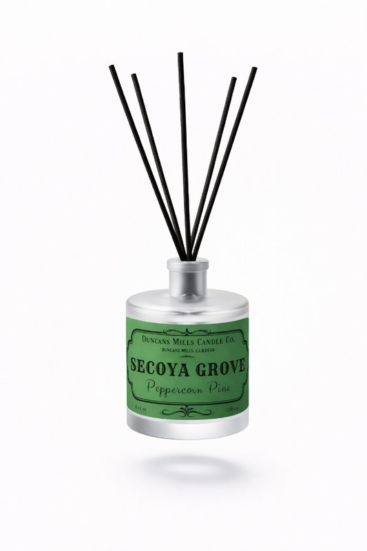 A reed diffuser bottle with a green label reading 'Secoya Grove Peppercorn Pine' and black reed sticks, shown on a clean white background.