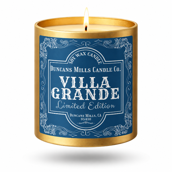A lit soy wax candle in a cylindrical gold metal tin with a blue label reading 'Duncans Mills Candle Co. Villa Grande Limited Edition' on a white background.