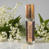 Whisper Rollerball Perfume displayed with flowers evoking its delicate and enchanting fragrance.