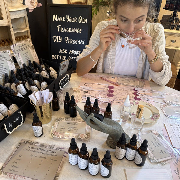 Woman at a table with fragrance blending materials.